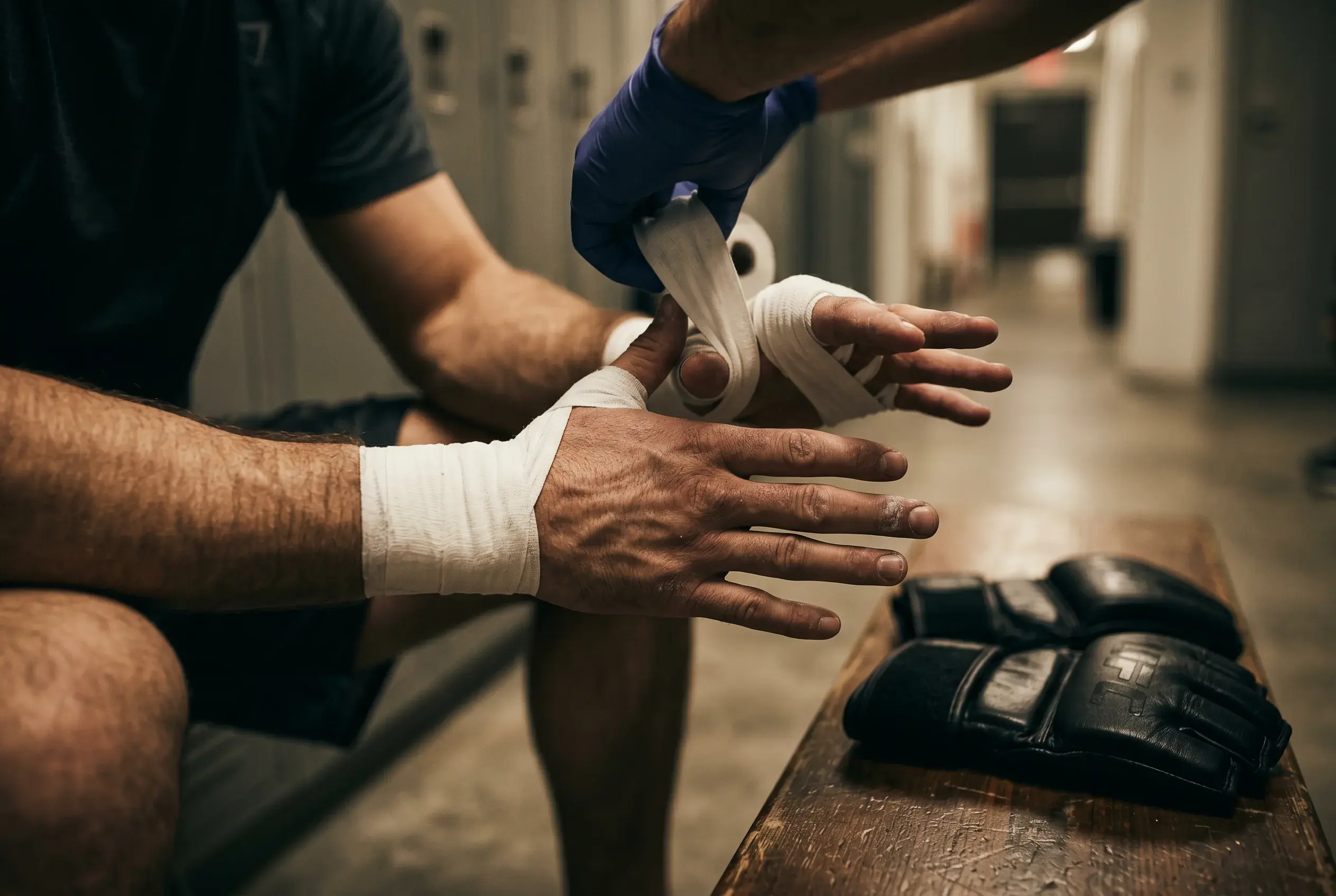 MMA fighter having hand wraps applied in the corner before a UFC bout, focused close-up of the wrapping process